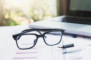 gafas sobre escritorio con computador al fondo